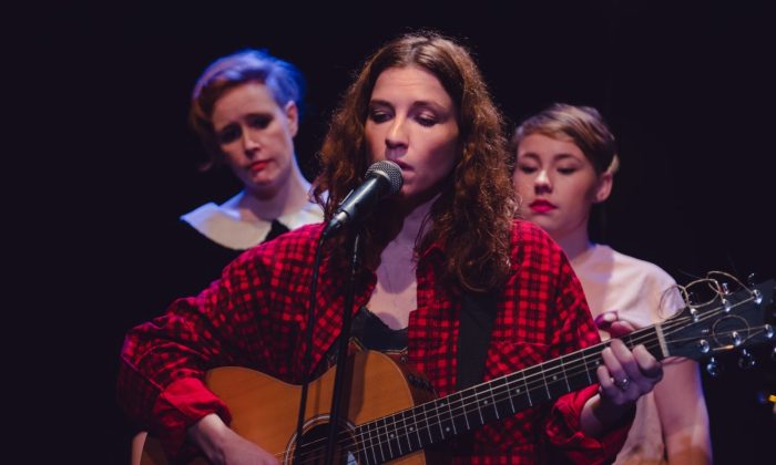 Rosie Doonan sings into a microphone whilst playing a guitar with Kylie and Georgie look on. Image from Roar R&D which later became Ask Me Anything