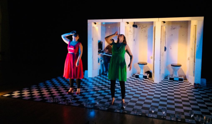 Thirsty production shot showing two females drinking alcohol in a club toilet