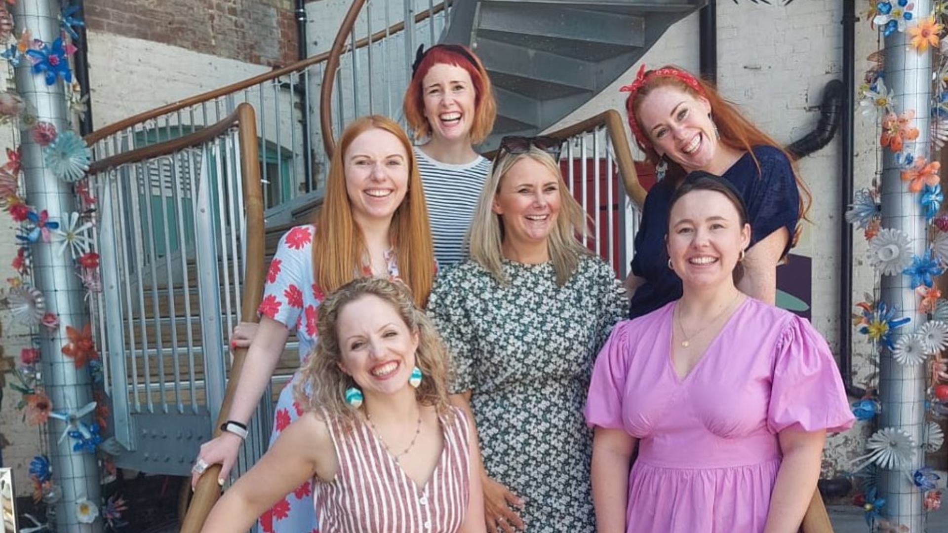 Image shows The Paper Birds team standing on the steps together smiling and happy