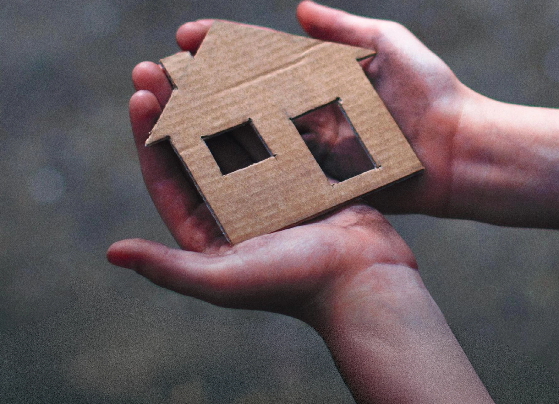 Home Sweet Home image - cardboard house being held carefully in hands